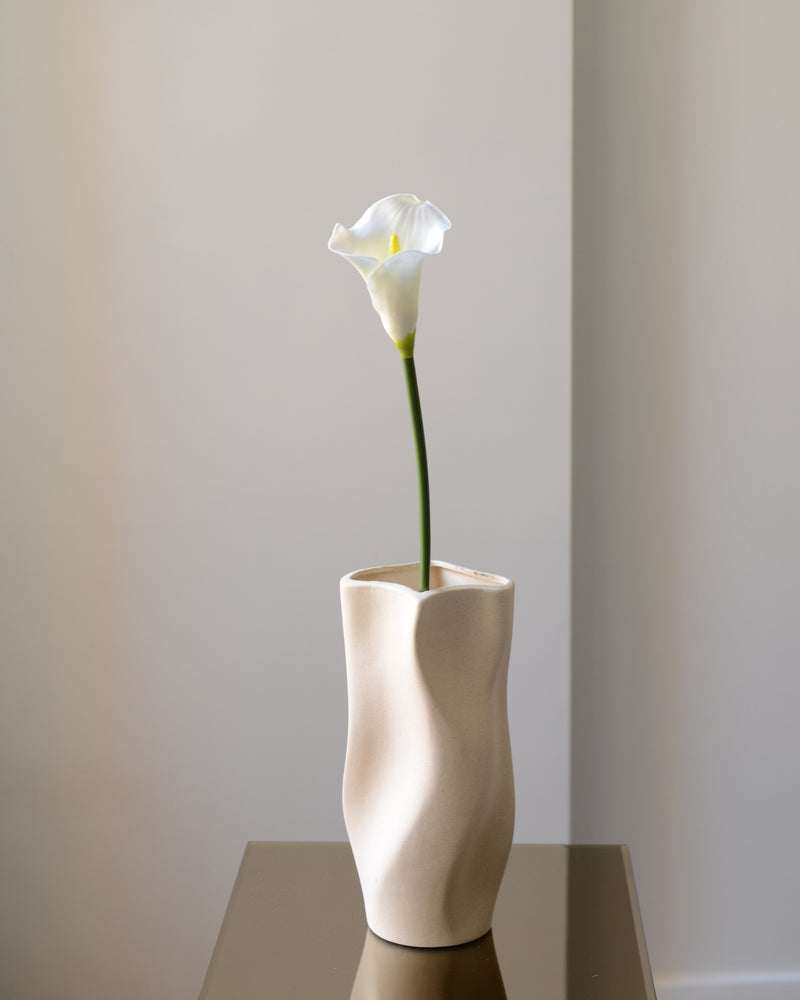 Vores kunstige calla lilje i klassisk hvid er en tidløs og elegant blomst, der tilfører ro og raffinement til enhver indretning. Med sin karakteristiske tragtform og glatte, silkebløde overflade ligner den ægte vare til forveksling – både i udtryk og struktur.
Stilken er fleksibel og naturtro med diskrete farvenuancer, som fuldender det realistiske look. Smuk alene i en slank vase eller som del af en buket, hvor den tilfører et stilrent og sofistikeret præg. Et ideelt valg til dig, der ønsker vedvarende sk