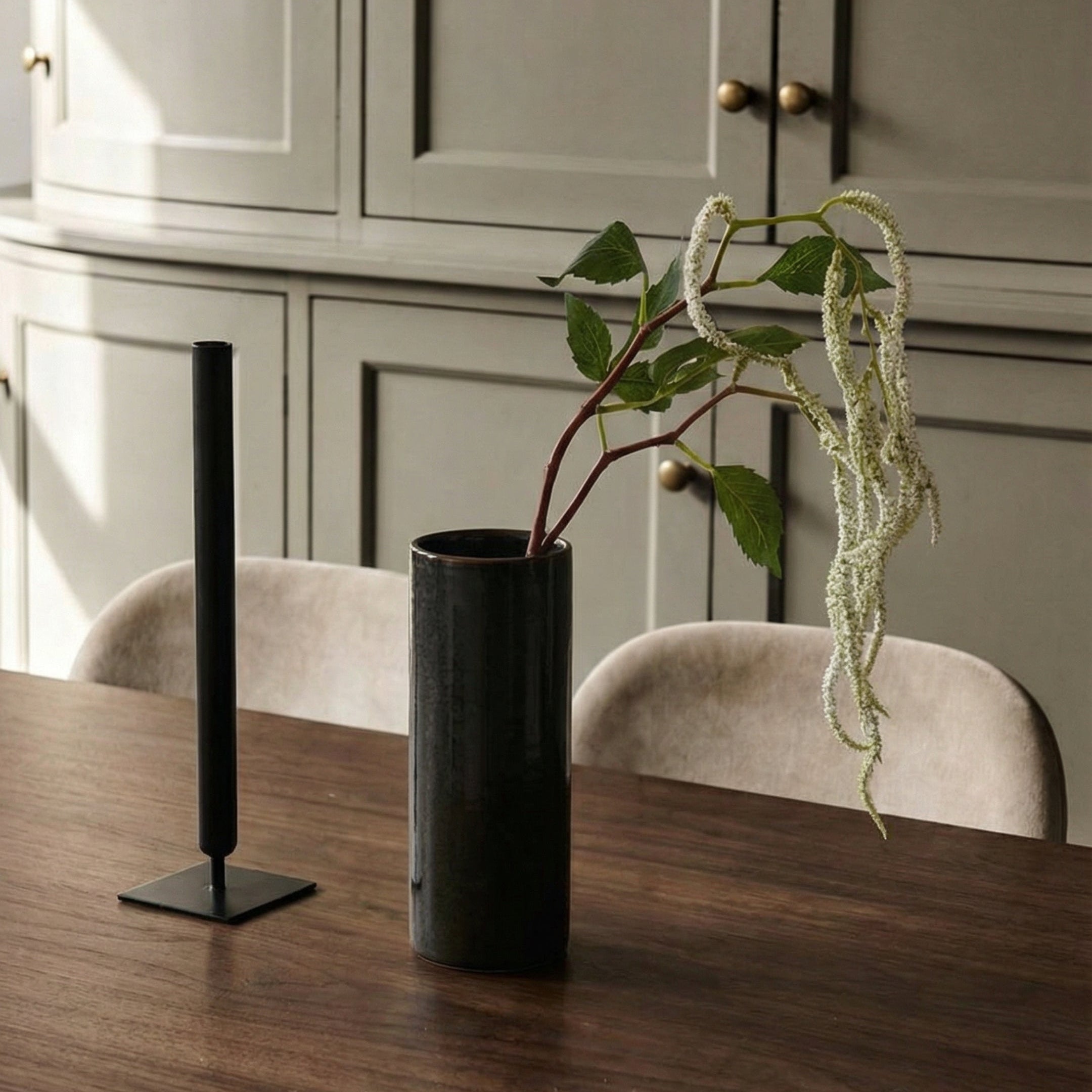 En enkelt hvid, hængende amarant i en sort vase på et spisebord