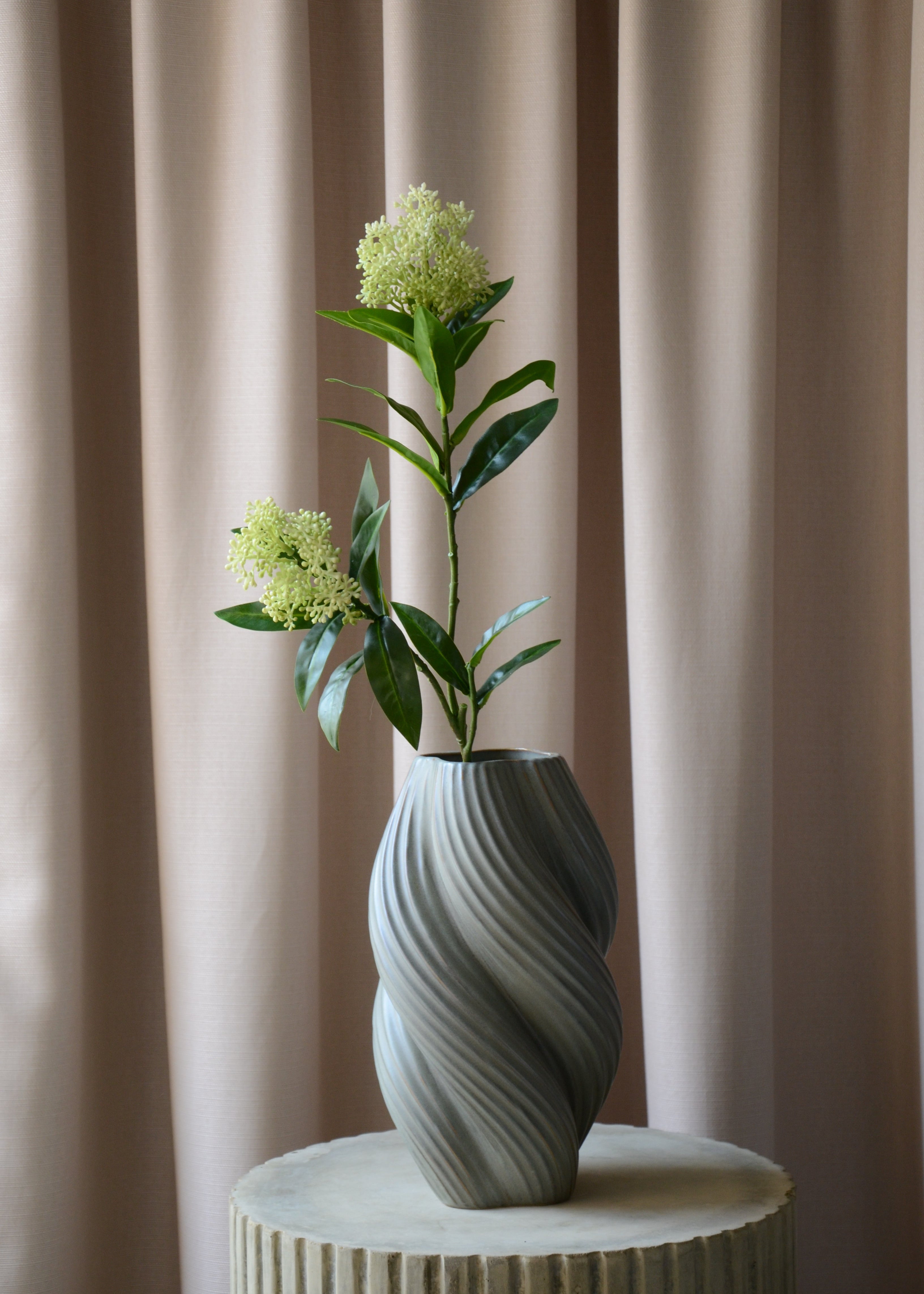 Den kunstige Skimmia med to hvid-grønne bærklaser er det perfekte valg, når du vil tilføje et elegant og friskt touch til din indretning. De mørkegrønne blade skaber en smuk kontrast til de lyse bær, som er udformet med stor omhu og realisme.&nbsp;

Den langvarige og vedligeholdelsesfri Skimmia står smukt alene eller tilføjer et sofistikeret og levende element til en buket med andre kunstige blomster.