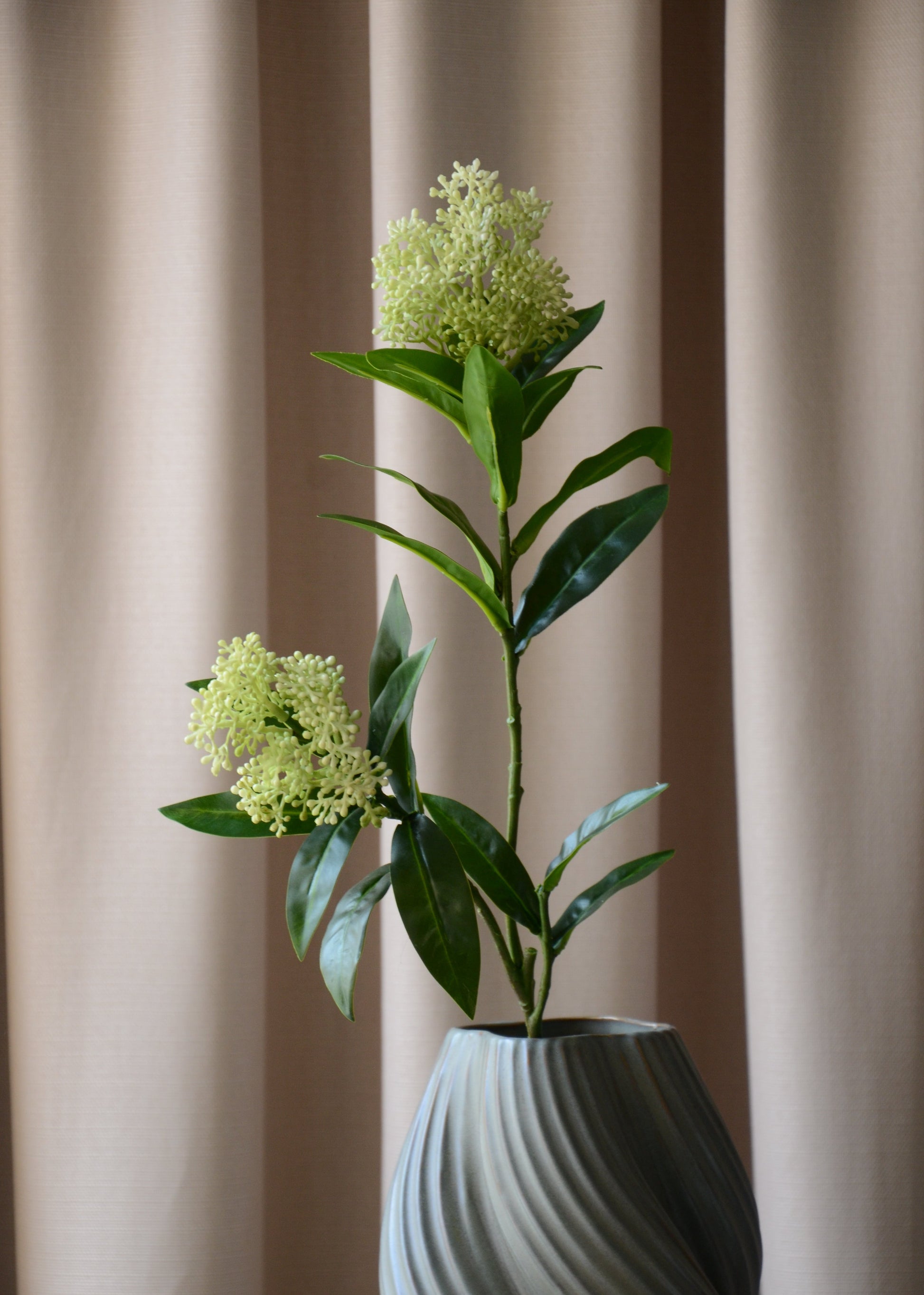 Den kunstige Skimmia med to hvid-grønne bærklaser er det perfekte valg, når du vil tilføje et elegant og friskt touch til din indretning. De mørkegrønne blade skaber en smuk kontrast til de lyse bær, som er udformet med stor omhu og realisme.&nbsp;

Den langvarige og vedligeholdelsesfri Skimmia står smukt alene eller tilføjer et sofistikeret og levende element til en buket med andre kunstige blomster.