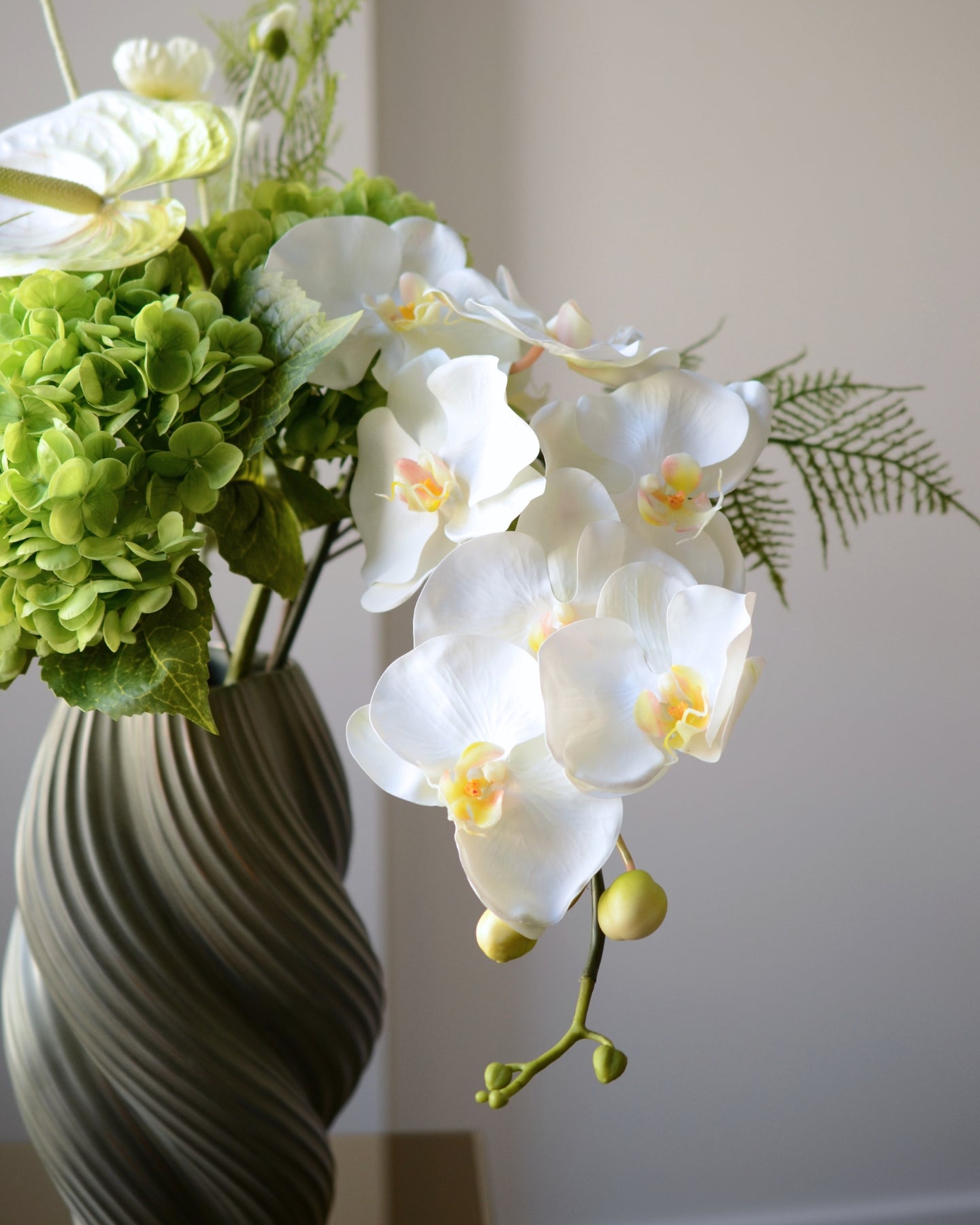 En elegant evighedsbuket i klare hvide og grønne nuancer, hvor den smukke orkidé får lov at træde i karakter med sit yndefulde udtryk. De fine, silkebløde kronblade er udformet med stor omhu og føles næsten som en ægte blomst. Kombinationen af lyse toner og friske grønne elementer skaber et roligt, sofistikeret udtryk – perfekt til dig, der elsker et let og eksklusivt look i hjemmet.
Både tidløs og moderne på én gang.