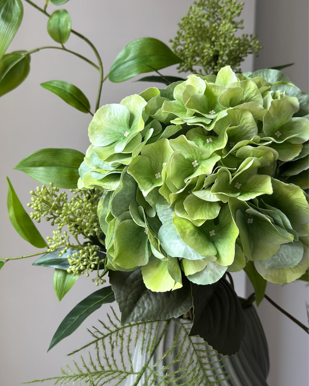 Evighedsbuket af kunstige blomster i grøn.  I midten er en stor, grøn kunstig hortensia