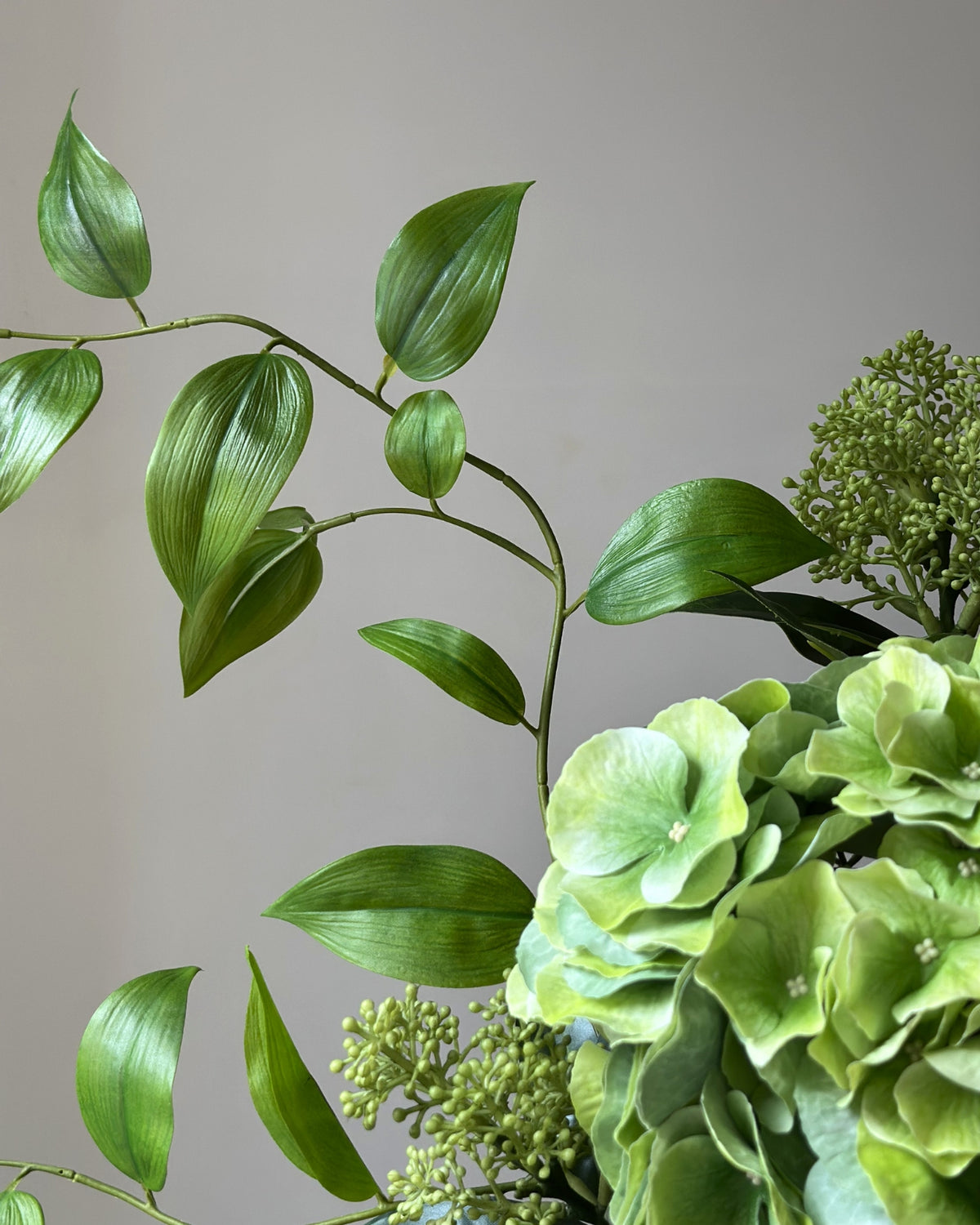 Evighedsbuket af kunstige blomster i grøn.  I midten er en stor, grøn kunstig hortensia