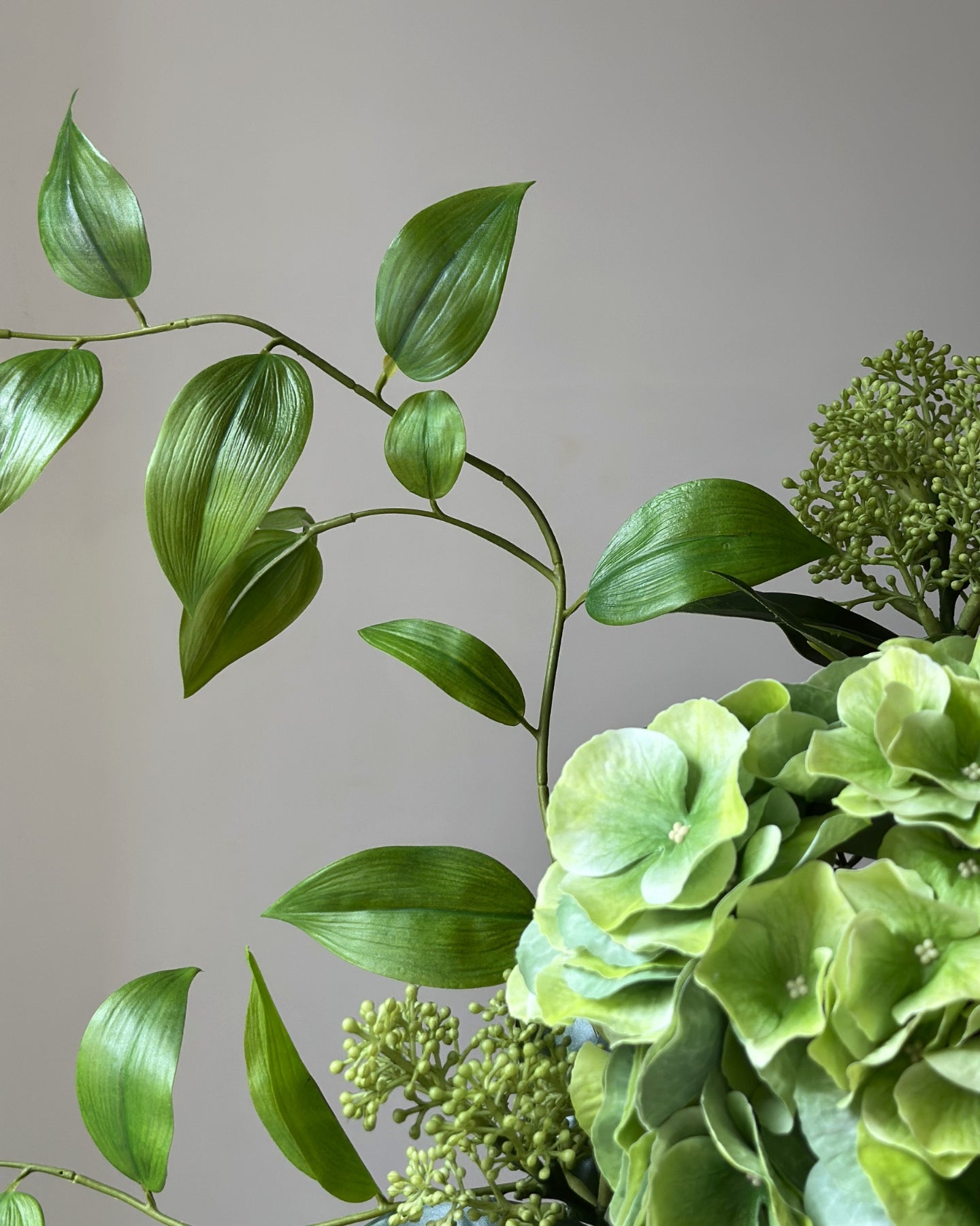 Evighedsbuket af kunstige blomster i grøn.  I midten er en stor, grøn kunstig hortensia