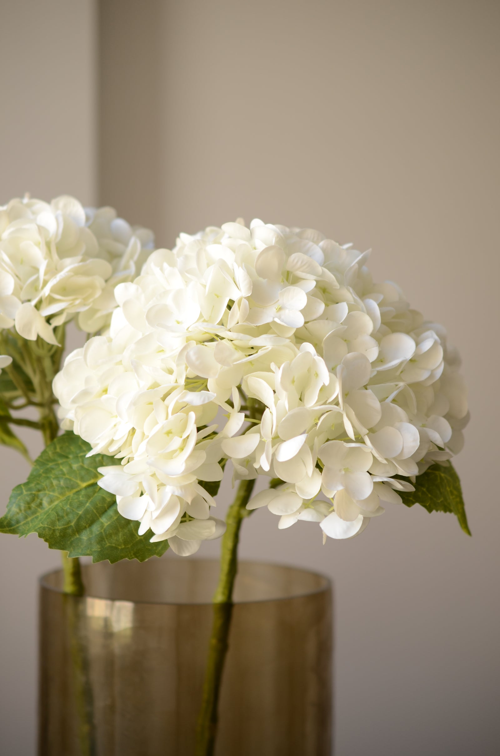 Den kunstige hvide hortensia er en iøjnefaldende blomst, der tilføjer et elegant element til en buket. Med sine fyldige blomsterhoveder i smukke, rene nuancer skaber den en indbydende atmosfære. De detaljerede blomster og de grønne blade giver et naturligt og realistisk udtryk, mens den langvarige kvalitet gør den til en vedligeholdelsesfri løsning.

Stilken måler 49 cm.