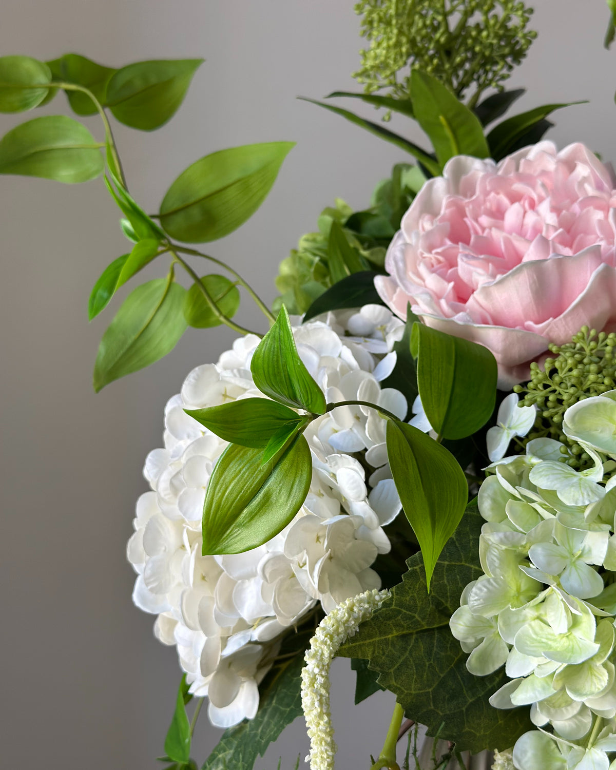 Blush Arbour buket fra Bloomgaard med lyserød pæon, hortensiaer og hvid amarant i grågrøn vase på en piedestal