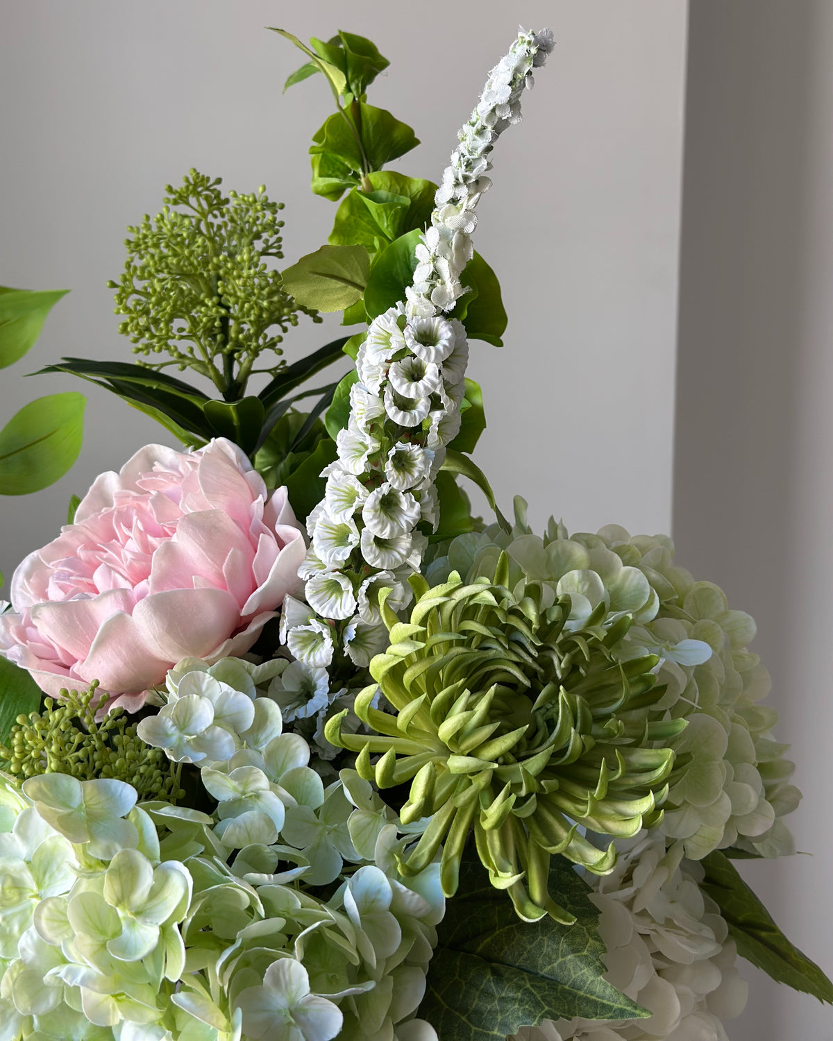 Blush Arbour buket fra Bloomgaard med lyserød pæon, hortensiaer og hvid amarant i grågrøn vase på en piedestal