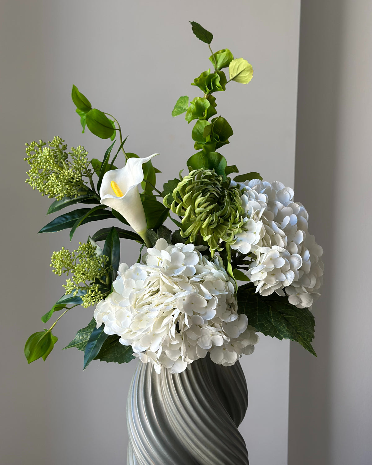 White Colonnade buket fra Bloomgaard i hvidt og grønt i grå vase på en piedestal