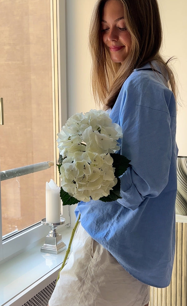Kunstig hortensia i hvid holdt ved siden af en ægte hortensia i hvid