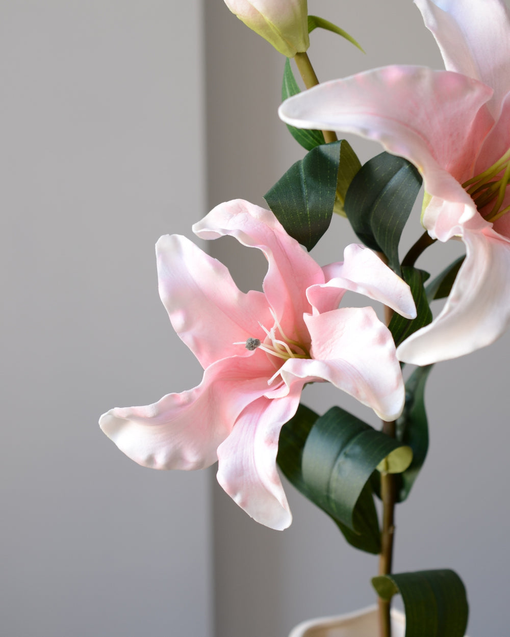 Vores kunstige lilje er udformet i en blid rosa-hvid nuance med silkebløde kronblade og et bølgende, naturligt udtryk. En yndefuld og iøjnefaldende blomst, der med sine to store hoveder og elegante knop skaber blikfang i enhver opstilling.&nbsp;

De let buede stilke og fine detaljer giver blomsten en livagtig fornemmelse, der føles næsten ægte. Smuk alene i en slank vase eller som centerpiece i en buket – den perfekte tilføjelse til dig, der ønsker vedvarende skønhed uden vedligeholdelse.

Stilken måler 92 