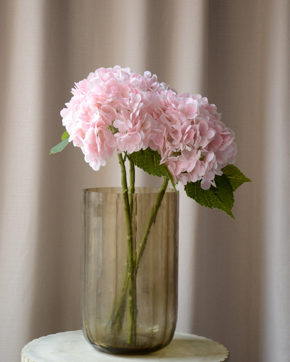 Den kunstige lyserøde hortensia er en delikat blomst, der tilføjer et romantisk og let element til enhver buket eller dekoration. Med sit fyldige blomsterhoved i sarte, smukke nuancer skaber den en farverig og indbydende atmosfære. Den detaljerede blomst og de grønne blade giver et naturligt og realistisk udtryk, mens den langvarige kvalitet gør den til en vedligeholdelsesfri løsning.

Stilken måler 49 cm.