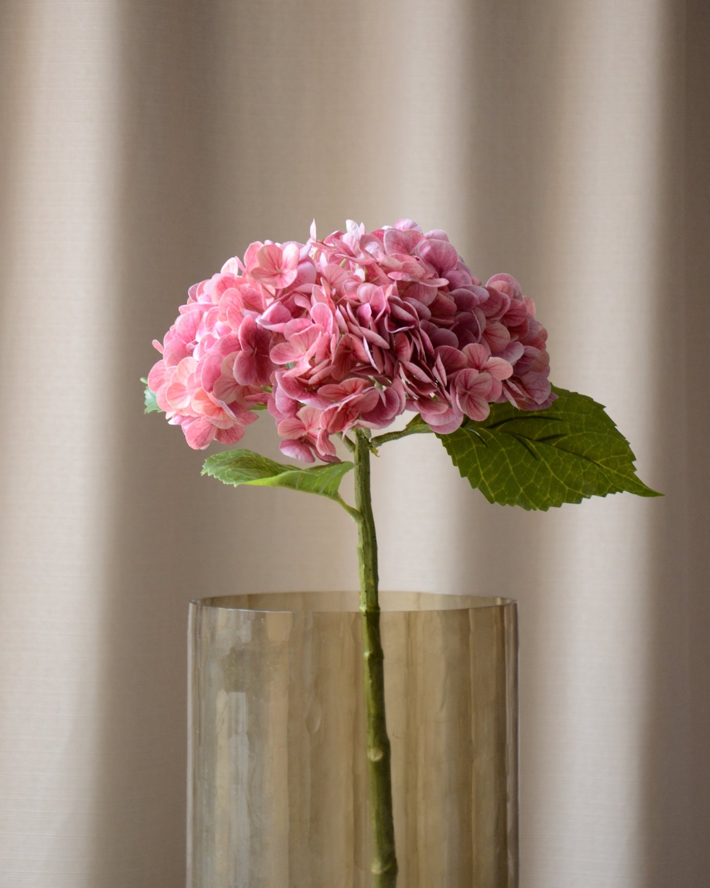 The artificial pink hydrangea is a striking flower that adds a romantic and vibrant touch to any bouquet or arrangement. With its lush flower heads in beautiful, warm shades, it creates a colorful and inviting atmosphere. The detailed blooms and green leaves give a natural, realistic look, while its long-lasting quality makes it a maintenance-free choice.

Stem measures 49 cm.