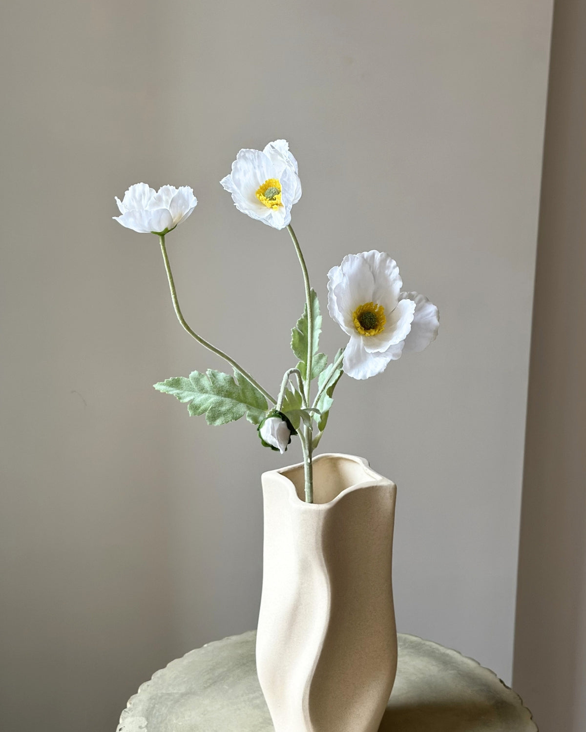 Kunstige, hvide valmuer. Tre udsprungne blomsterhoveder og en knop