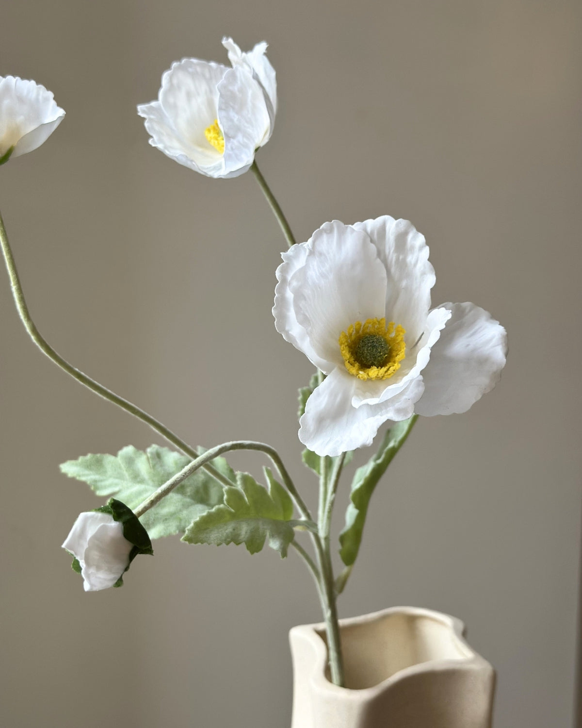 Kunstige, hvide valmuer. Tre udsprungne blomsterhoveder og en knop