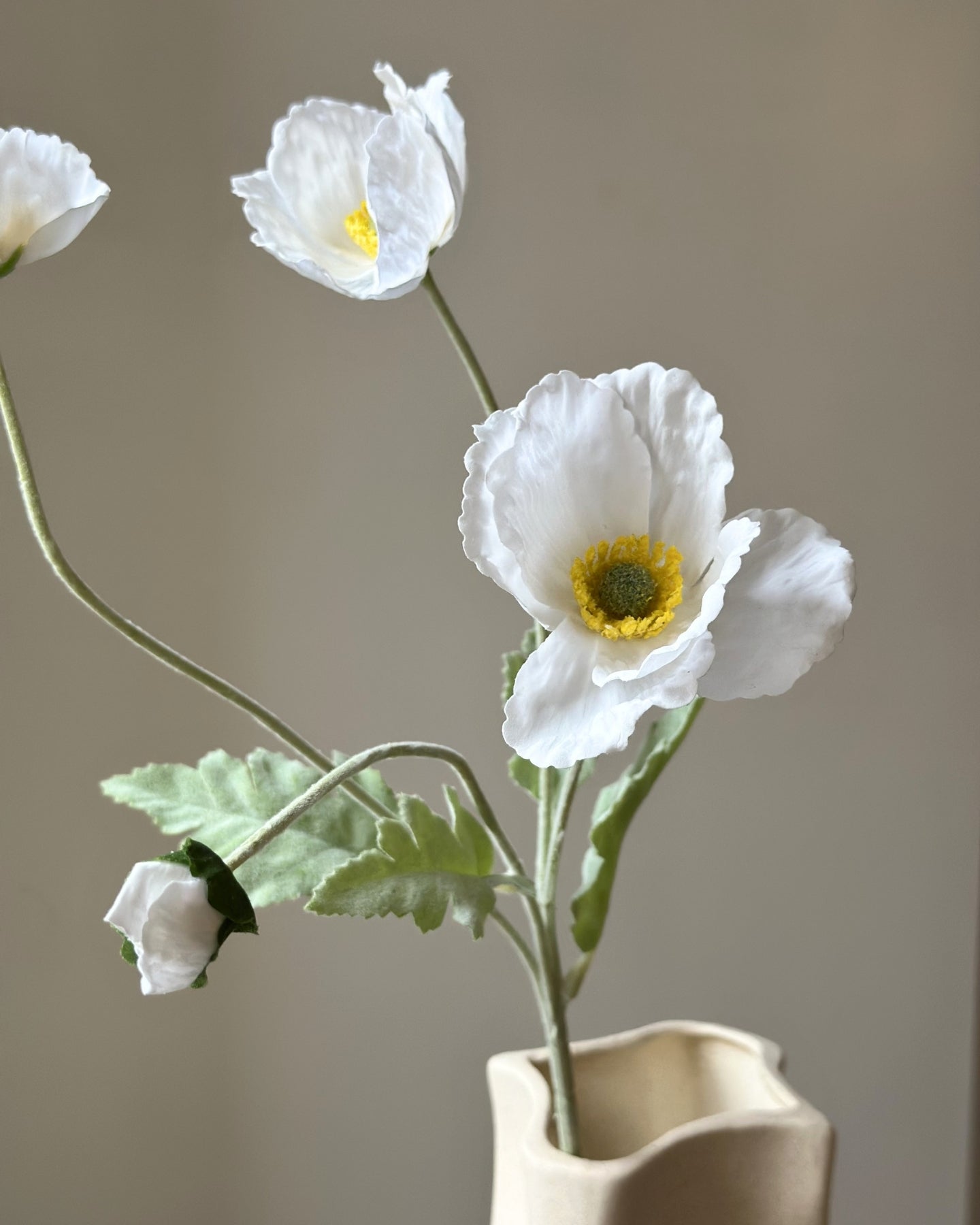 Kunstige, hvide valmuer. Tre udsprungne blomsterhoveder og en knop