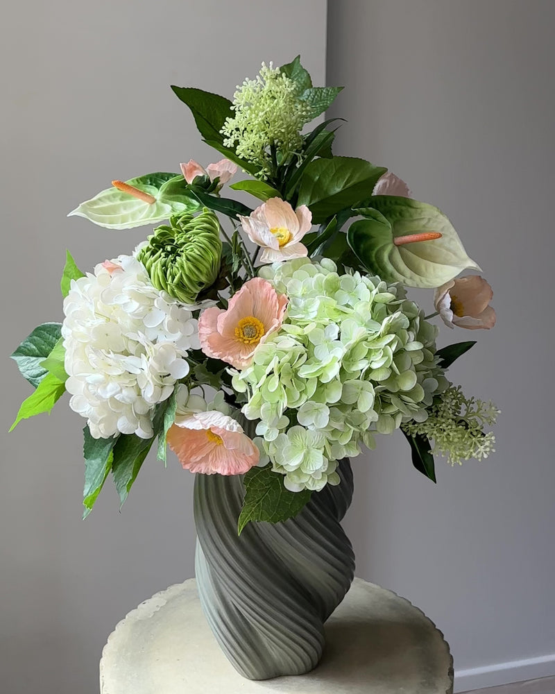 Blush Pavilion artificial bouquet with white and green hydrangeas, peach poppies, green anthurium and a green cactus dahlia bud in a grey-green twisted vase