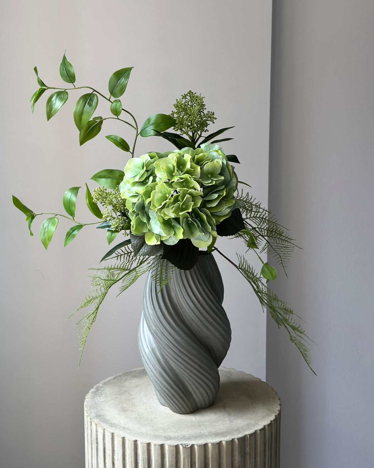 Evighedsbuket af kunstige blomster i grøn.  I midten er en stor, grøn kunstig hortensia