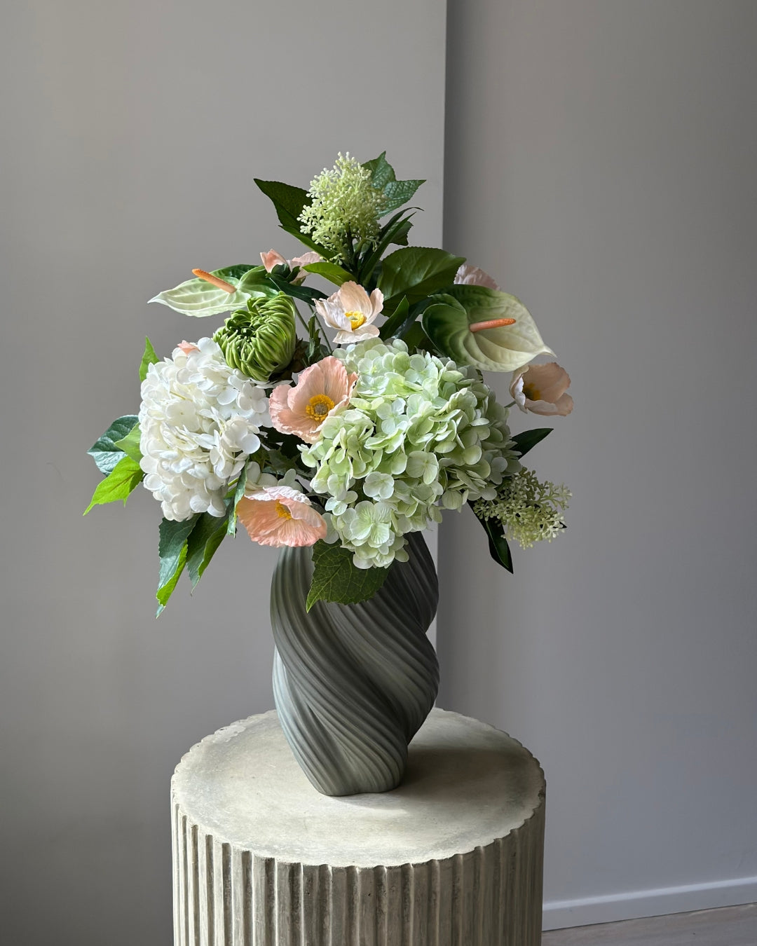Blush Pavilion artificial bouquet with white and green hydrangeas, peach poppies, green anthurium and a green cactus dahlia bud in a grey-green twisted vase